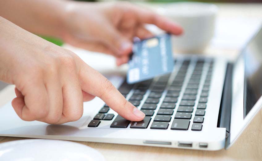 Hands holding a credit card and using laptop computer for online