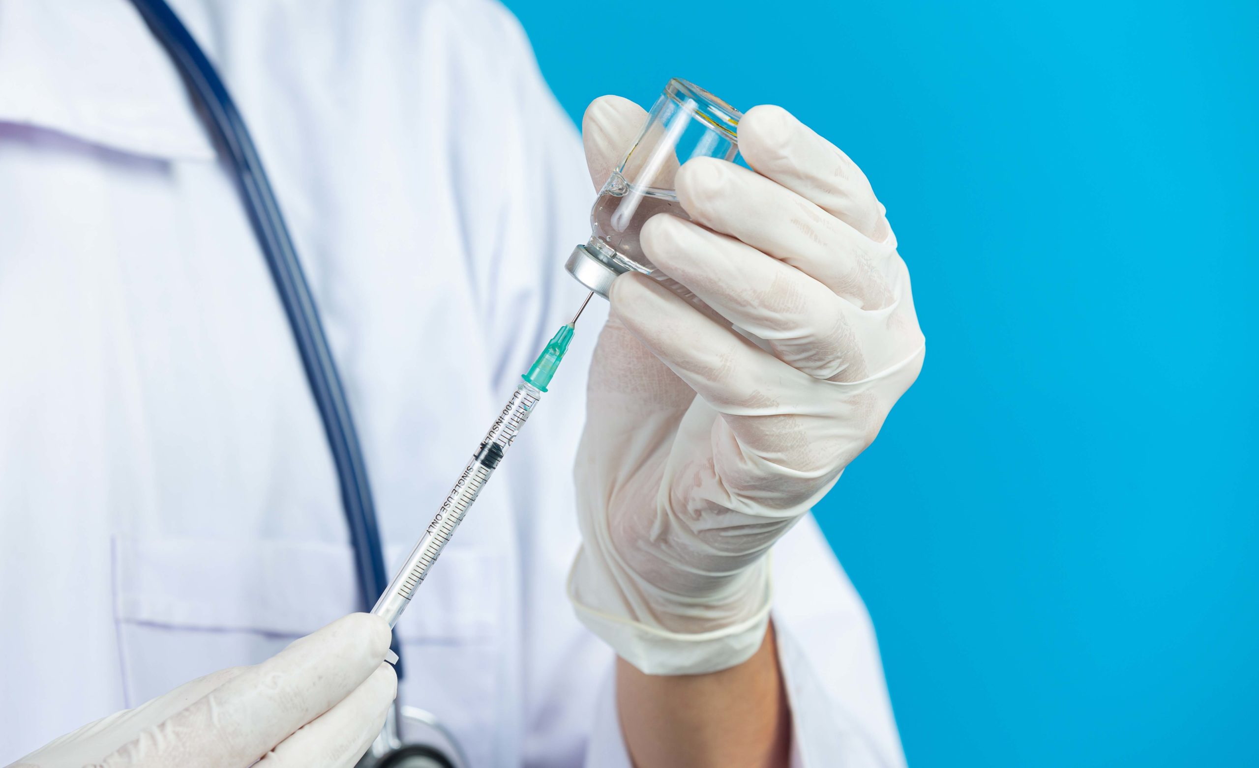 close up picture of docter's hands holding hypodermic syringe