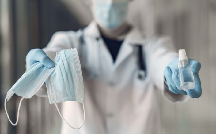 Doctor hold the antiseptic and masks in his hand