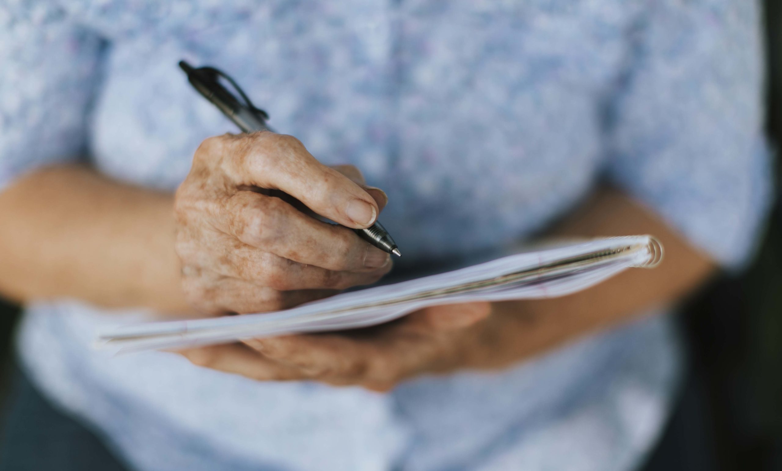 Senior woman writing down her memories into a notebook
