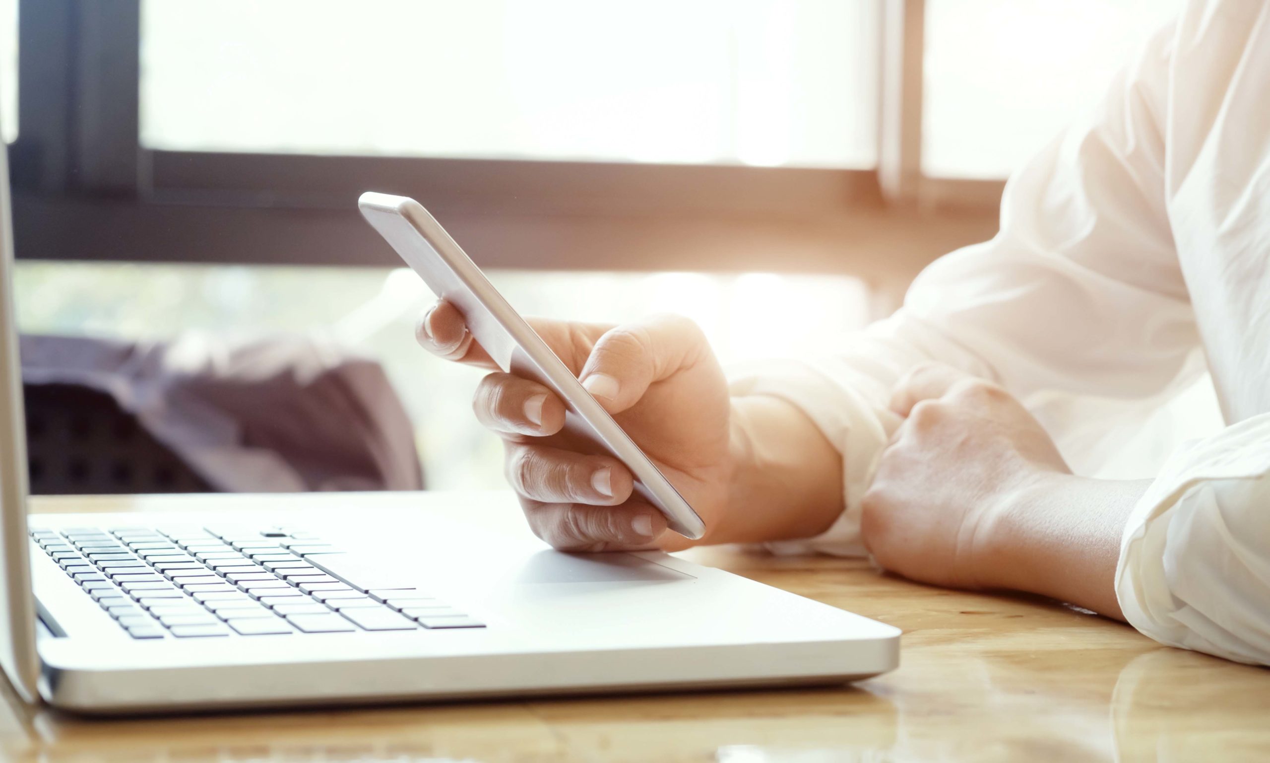Businessman using laptop and mobile phone.