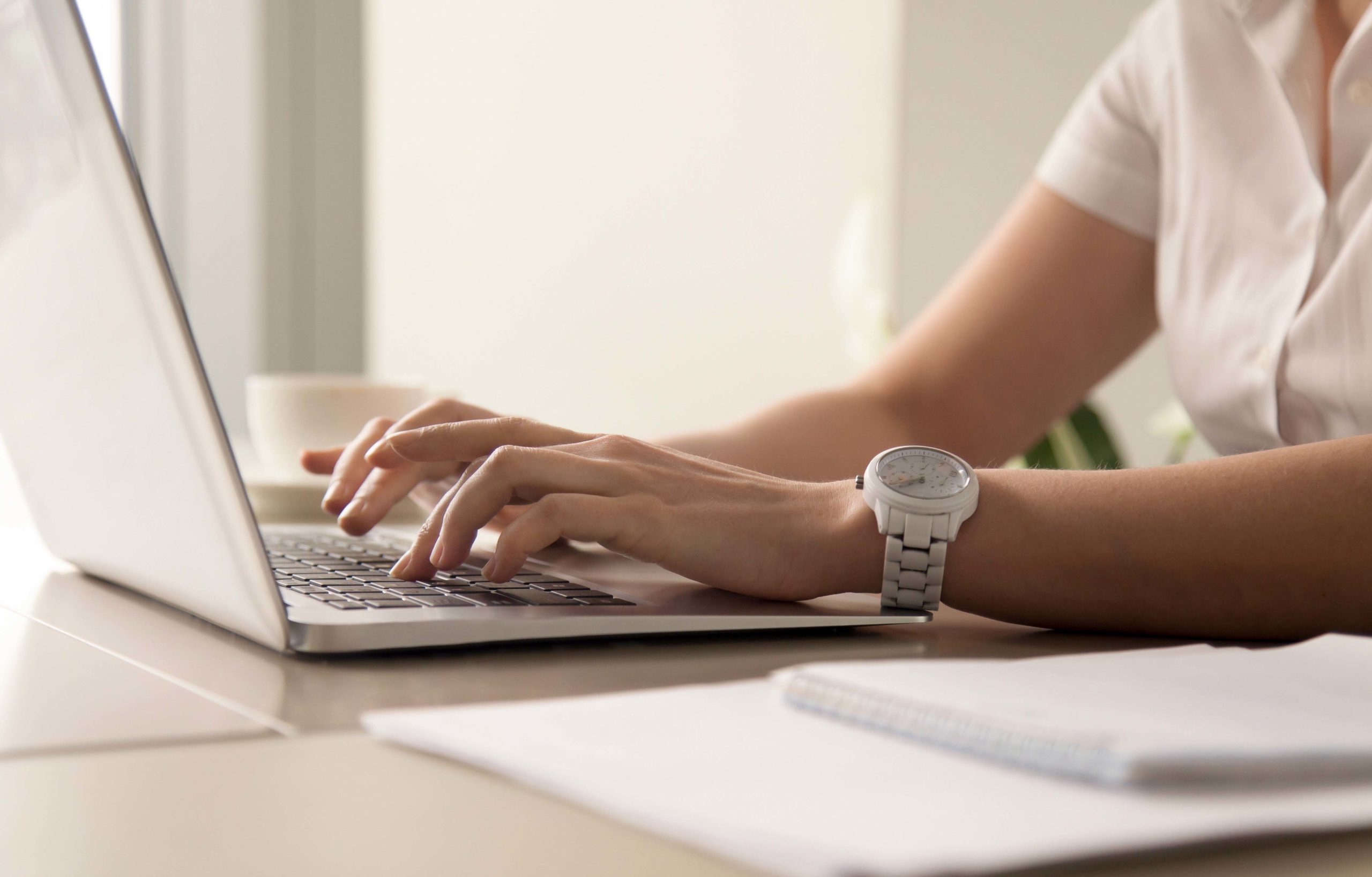 Womans hands typing on laptop at workplace