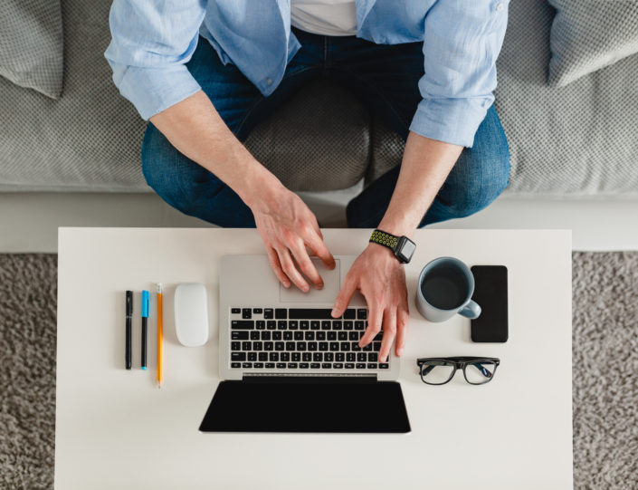 view on table workplace close-up man hands at home working typing on laptop online