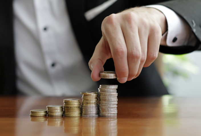 closeup-shot-businessman-s-hands-counting-stacks-coins-after-business-success